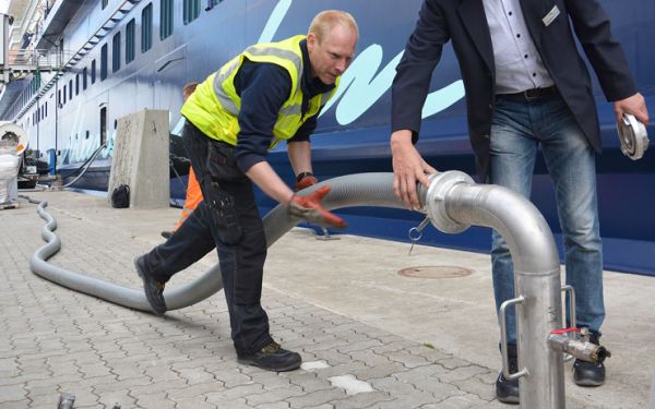 An employee of the PORT OF KIEL connects a hose