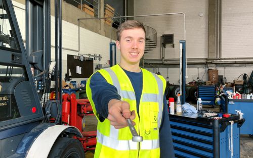 Mitarbeiter*in hält Schraubenschlüssel in die Kamera