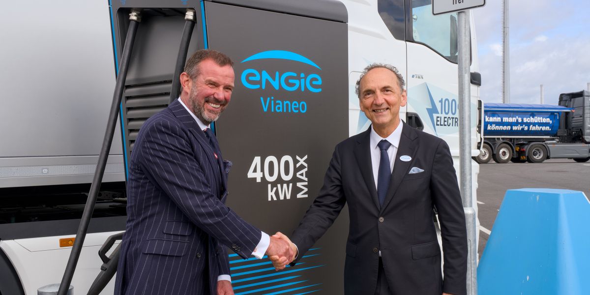 Frank Lacroix, ENGIE (rechts), und Dr. Dirk Claus, SEEHAFEN KIEL GmbH & Co. KG, schütteln sich die Hand vor einer E-Ladesäule.