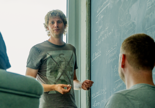 An employee of the IT department stands in front of the blackboard and writes down ideas.