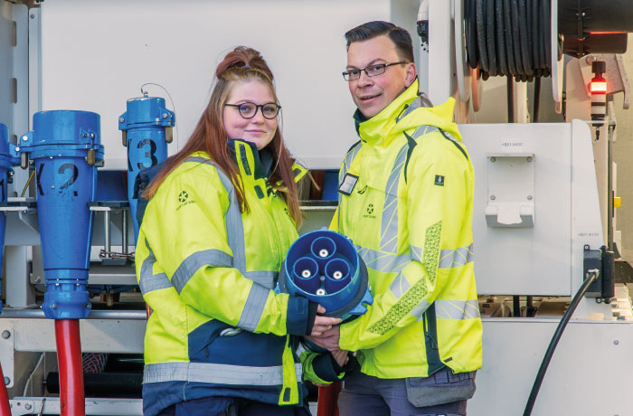 2 Kolleg*innen halten einen Landstromstecker für Schiffe